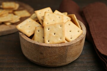 Tasty salty crackers on wooden table, closeup