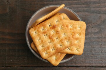 Tasty salty crackers on wooden table, top view