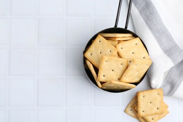 Tasty salty crackers on white tiled table, flat lay. Space for text