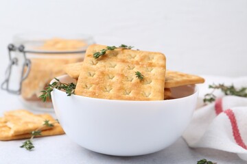 Tasty salty crackers and thyme on white table, closeup