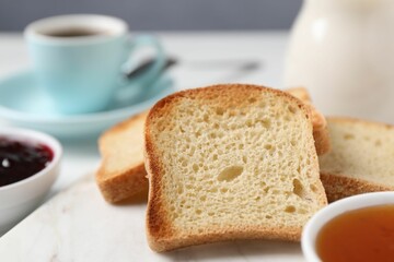 Slices of tasty toasted bread and jam on white table against grey background, closeup