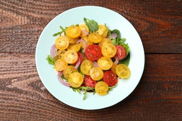 Fresh salad with yellow tomatoes on wooden table, top view