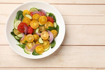Fresh salad with yellow tomatoes on wooden table, top view. Space for text