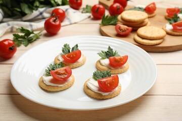 Tasty crackers with cream cheese, tomatoes and parsley on white wooden table, closeup
