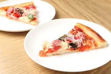 Slices of tasty pizza with thin smoked sausages served on wooden table, closeup