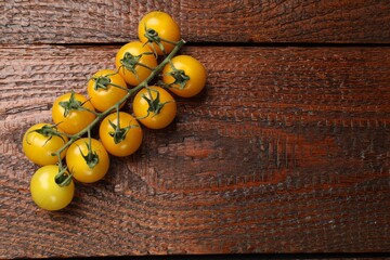 Ripe yellow cherry tomatoes on wooden table, top view. Space for text