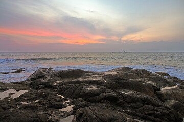 Sunset over rocky shoreline at Ventura beach with calm ocean and colorful sky