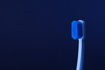 Close-up of a blue plastic toothbrush on a blue background. Space for text. Dentistry.