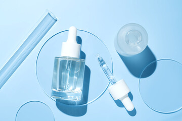 Cosmetic pipette serum on a petri dish on blue background. Cosmetology and pharmaceuticals concept....