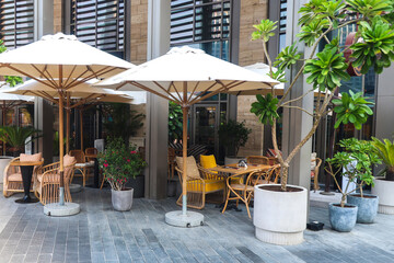Cozy street cafe with wooden furniture under sun umbrellas.