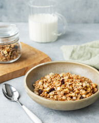 Homemade baked granola or muesli in a bowl on a light background with milk, spoon and napkn