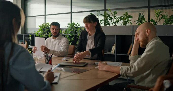 Businesswoman concludes the meeting exchanging final thoughts with colleagues before leaving the table in a modern office