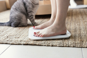 Young woman standing on scales at home, close up. Weight loss concept
