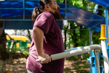 Fototapeta premium Plus-size man exercising outdoors: stretching, using resistance bands and public gym equipment with confidence and joy in spring weather