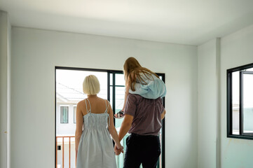 Family inspects their new home together, looking out the doors and imagining the future in their...