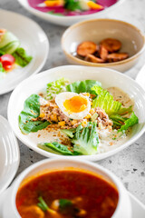 Fresh salad bowl with lettuce, corn, tuna, and a soft-boiled egg, accompanied by soup and vegetables. Vibrant, healthy, and appetizing meal ideal for food photography and culinary presentations.