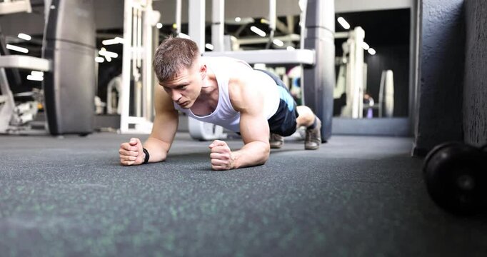 Sportsman does plank exercise during rigorous workout in gym. Young man performs strength and endurance maintaining focus on fitness routine