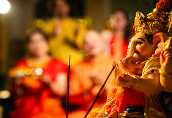 Indian family offering aarti to Ganpati idol at home with festive decor and traditional wear