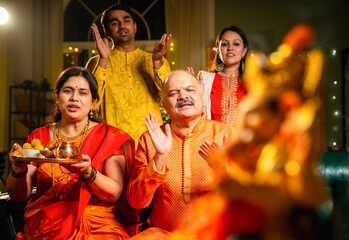 Indian family offering aarti to Ganpati idol at home with festive decor and traditional wear
