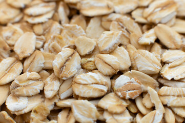 Close-up macro shot of raw oat flakes in shallow depth of field. Side view.