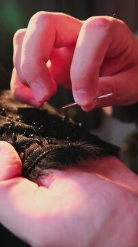 A master sews national Arab clothes abay with a needle and thread in his atelier