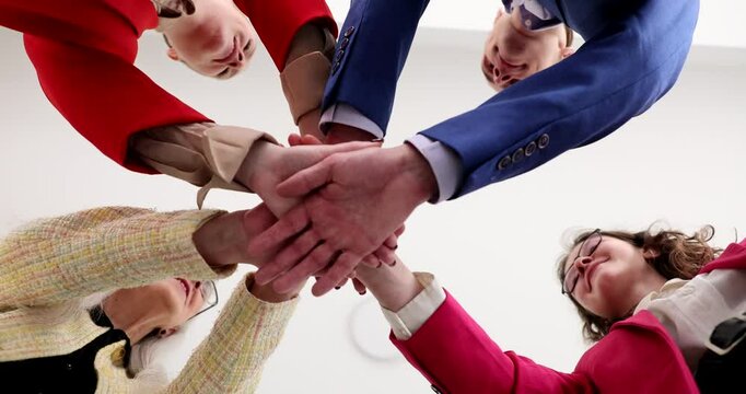 Corporate team interlocks hands representing collective strength and collaborative spirit in office. Employees show professional synergy in workplace