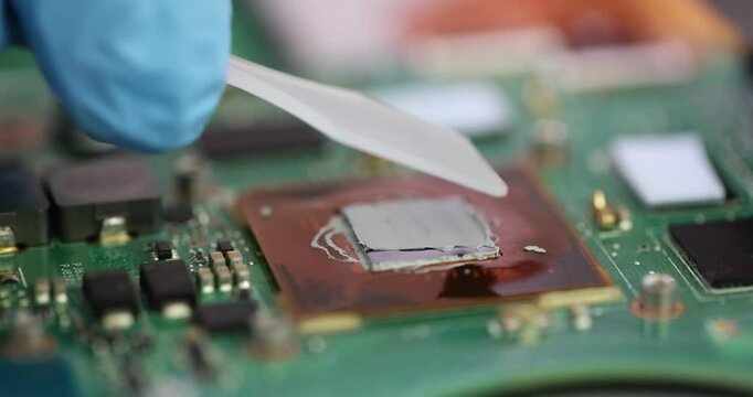 Technician carefully applies thermal paste to computer processor at workplace. Employee ensures efficient heat dissipation and optimal performance