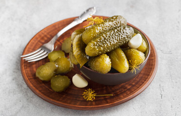 Tasty homemade cucumbers in a brown ceramic bowl on a gray textured background