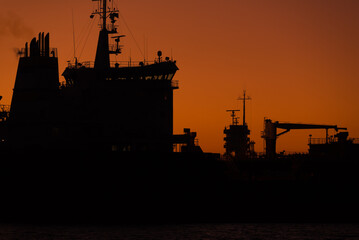SUNRISE OVER THE SEAPORT - Ship enters port against background of the lighthouse 