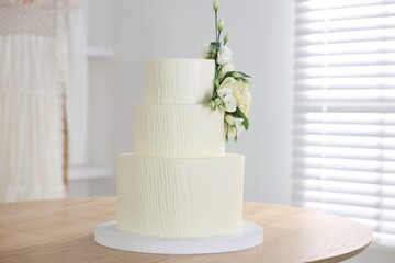 Delicious wedding cake with floral decor on wooden table indoors