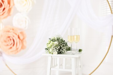 Glasses of champagne and wedding bouquet on table indoors