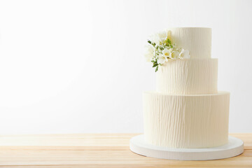 Delicious wedding cake with floral decor on wooden table against white background, space for text