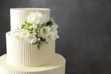 Delicious wedding cake with floral decor on grey background, closeup. Space for text
