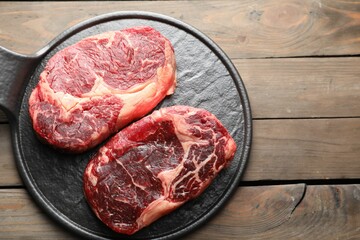 Pieces of raw beef meat on wooden table, top view. Space for text