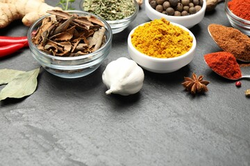 Different aromatic spices on black table, closeup. Space for text