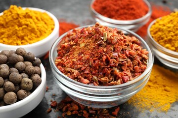 Different aromatic spices in bowls on dark table, closeup