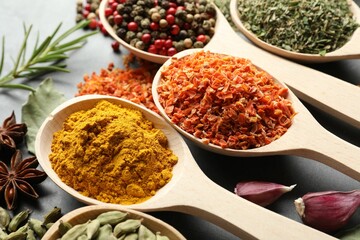 Many different spices in spoons on grey table, closeup