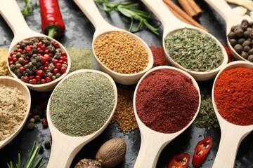 Many different spices in spoons on grey table, closeup