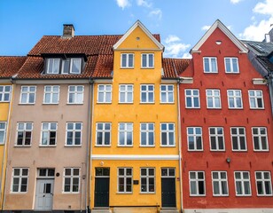Fototapeta premium Three colorful historic houses in a row. Beige, yellow, and red buildings with white-framed windows. Charming old-world architecture.