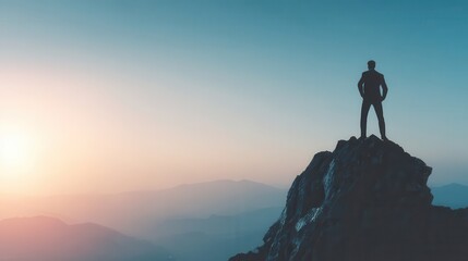 Silhouette of a person standing atop a mountain peak at sunrise.