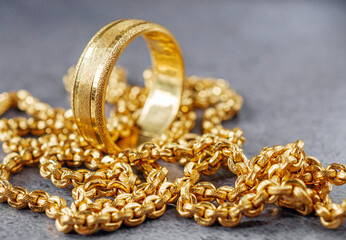 Gold price, gold jewelry, close-up of gold ring and gold necklace on grey background.