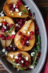 Obraz premium Roasted pears are beautifully arranged in a serving dish, garnished with fresh cranberries and crumbled goat cheese, perfect for a holiday celebration or gathering