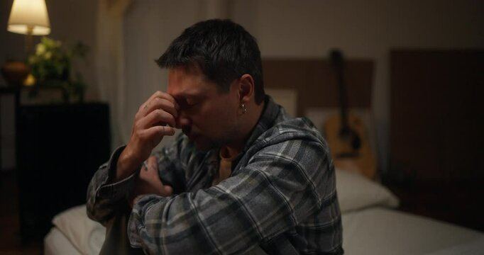 Sad Desperate Male Artist In Checkered Shirt Rubs Bridge Of Nose And Covers Face With Hands After Hard Day In Evening