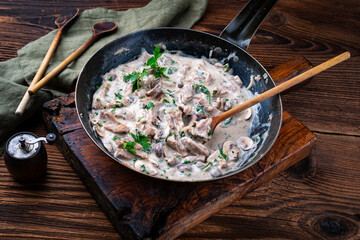 Traditional Swiss Zürcher geschnetzeltes from veal with mushrooms in cream sauce served as close-up in an iron skillet