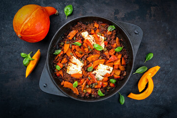 Greek style minced beef meat ragout stew with pumpkin, feta sheep cheese and capers in tomato sauce served as top view in cast iron pan
