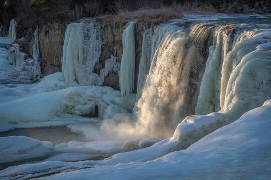 Icy waterfall in winter landscape with snow and sunshine