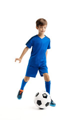 Sporty young boy in blue sport outfit playing with classic soccer ball over white background