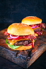 Classical cheeseburger with beef patty, cheese and bacon served as close-up with onion rings and...