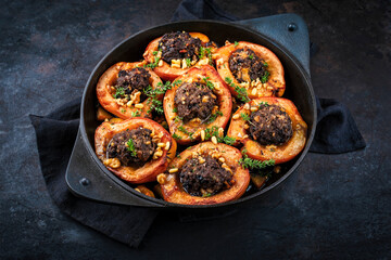 Traditional half quince stuffed with minced lamb meat, herbs and pine nuts as close-up in cast iron skillet