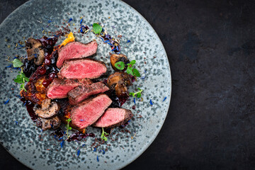 Barbecue dry aged venison steaks - deer entrecote cut english medium roasted served with grilled mushrooms, fruit berry sauce and panettone herbs